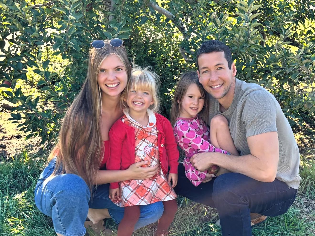 Sarah and Chase Beatty with their two daughters in an apple orchard