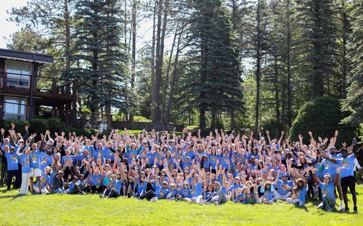 The whole Michigan 2026 retreat together on the lawn, hands in the air