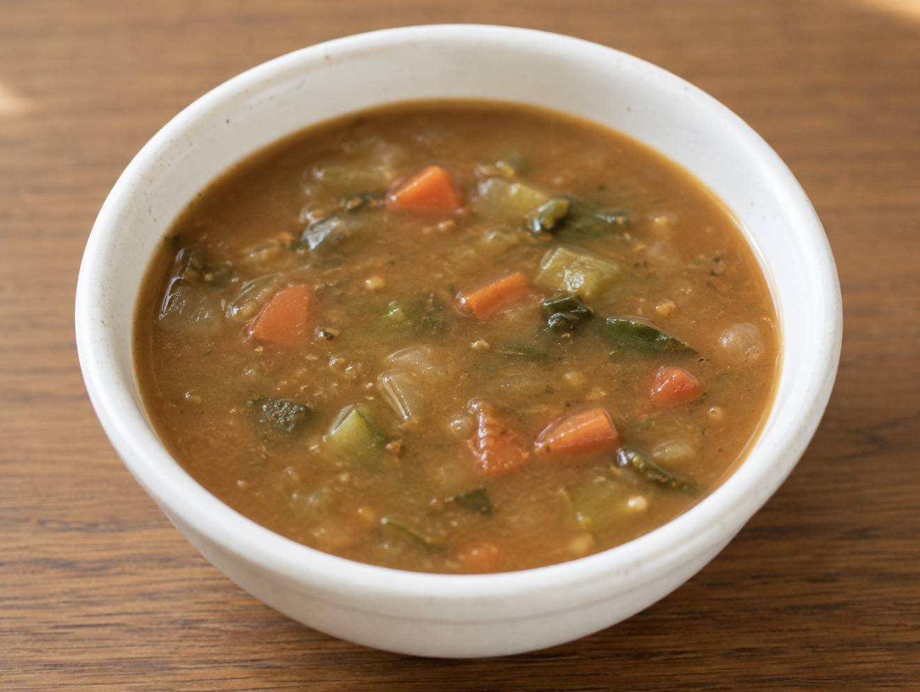 A white bowl of vegetable and lentil soup