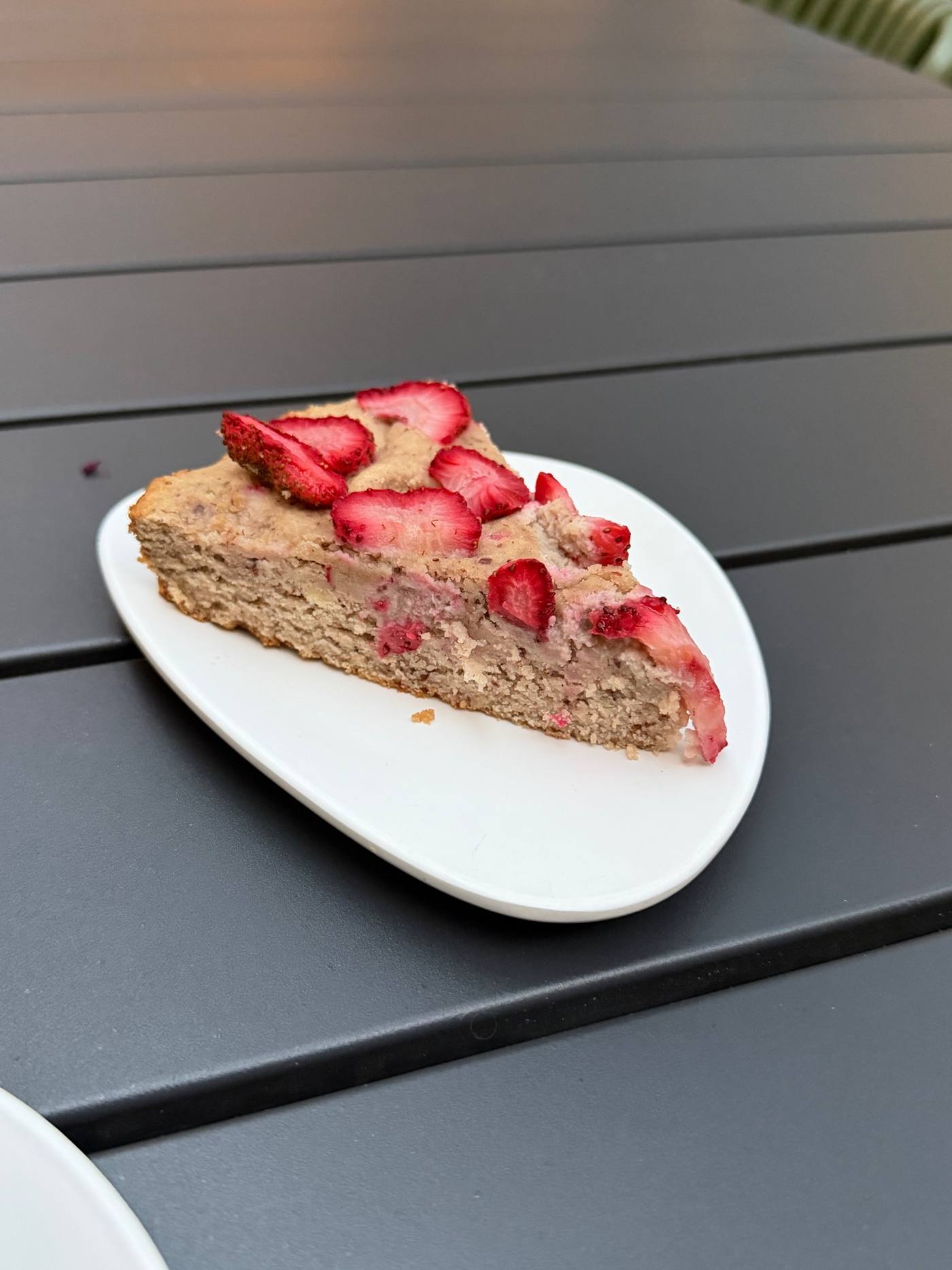 A slice of strawberry cake topped with fresh sliced strawberries