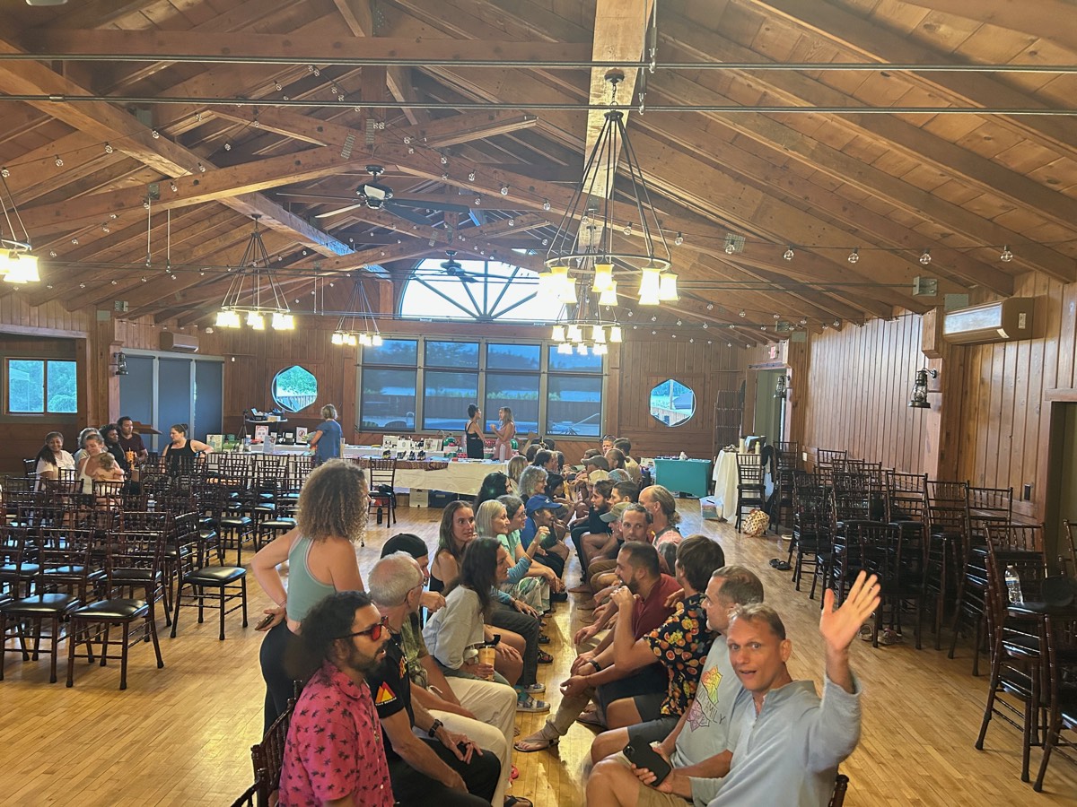 Dozens of guests seated in two long rows facing each other for Speed Dating night in the wood-beam great hall at a Vegan Wellness Retreat