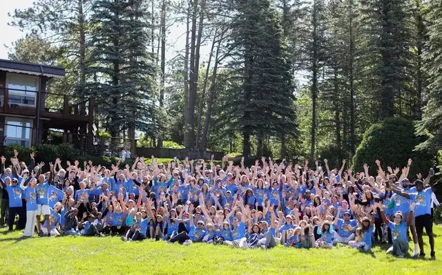 Hundreds of VWR guests of all ages in blue shirts with hands raised