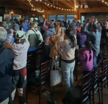 A packed hall of VWR guests on their feet with hands raised
